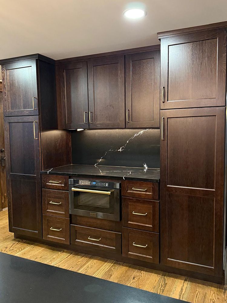 Dark wood kitchen cabinets with built-in oven, drawers, and countertop.