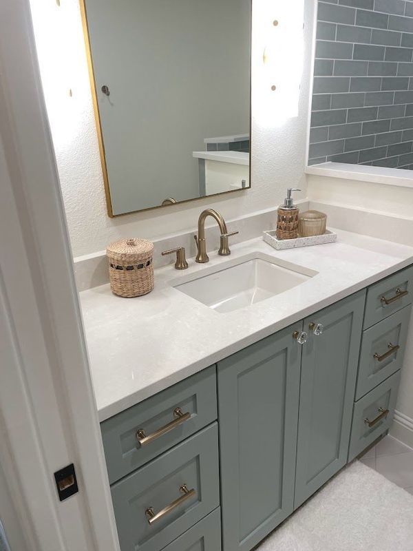 A bathroom with a sink , mirror and cabinets.