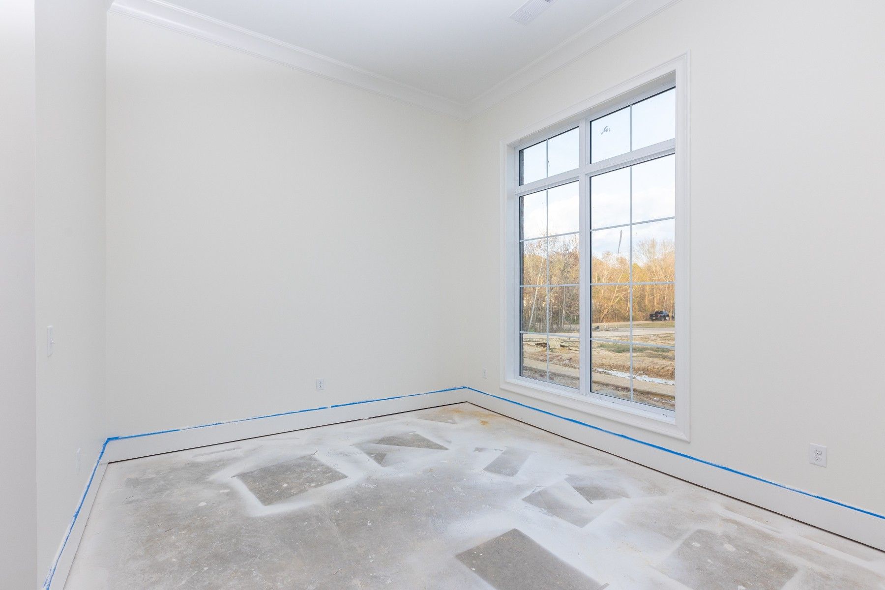 An empty room with a large window and a concrete floor.