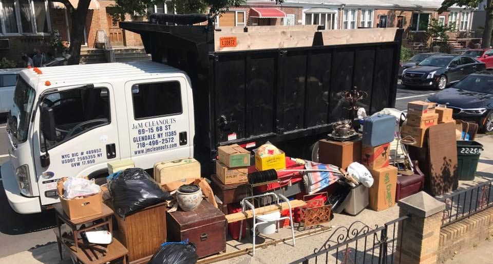 White truck filled with discarded furniture and boxes on a city street, ready for removal.