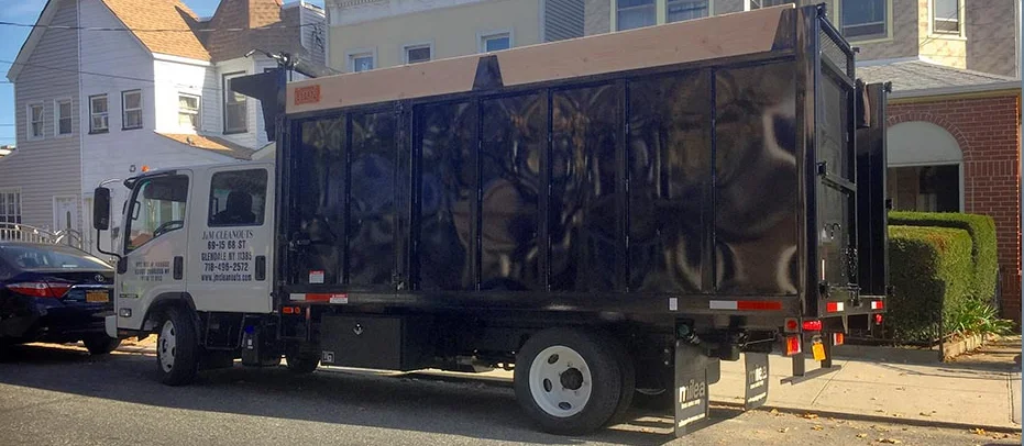 A black dump truck parked on a street in front of residential houses.