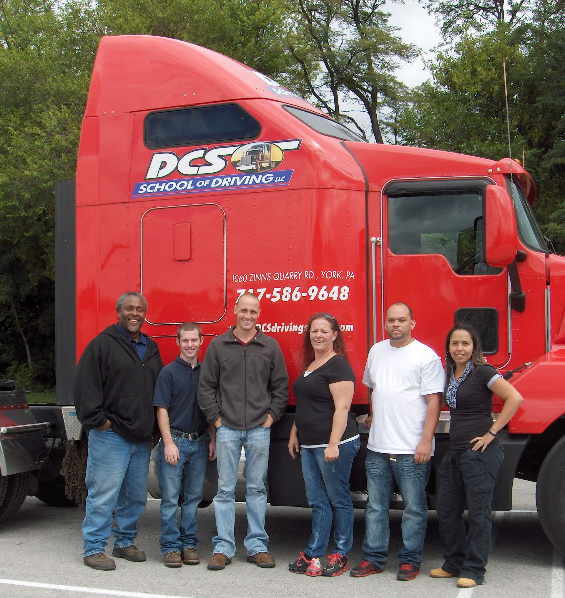 A group of people standing in front of a red dcs truck