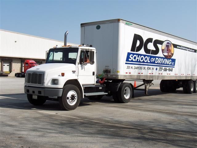 A dcs school of driving truck is parked in a parking lot