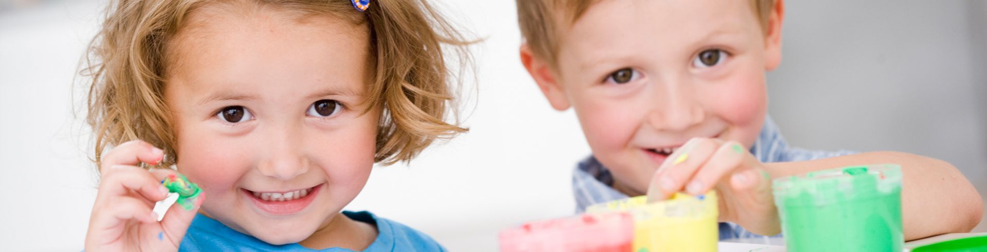 A boy and a girl are playing with clay and smiling