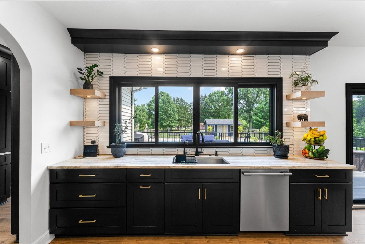 Modern kitchen with black cabinets, white textured backsplash, floating shelves, and a window above the sink.
