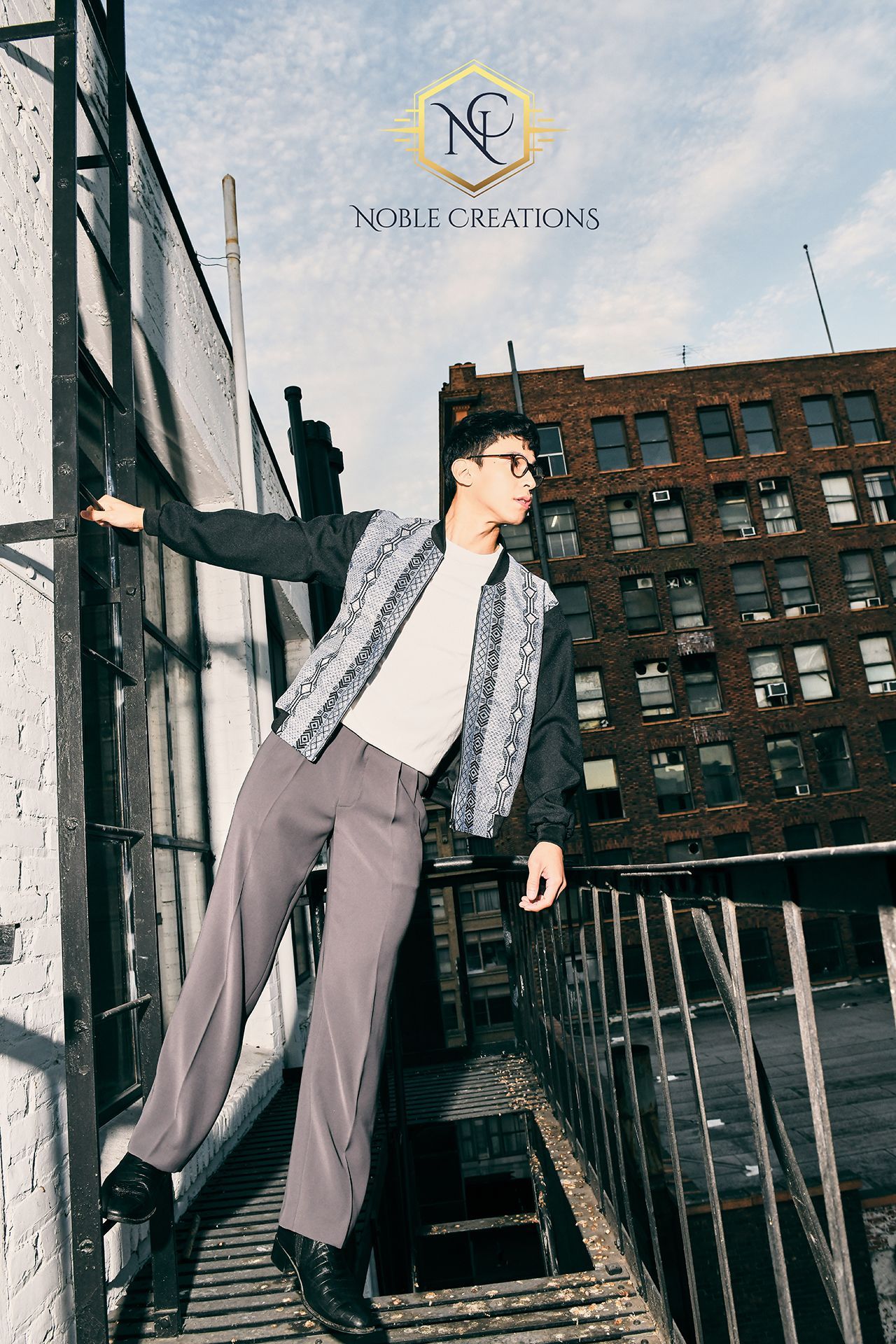 Man stands on a metal fire escape against a brick building