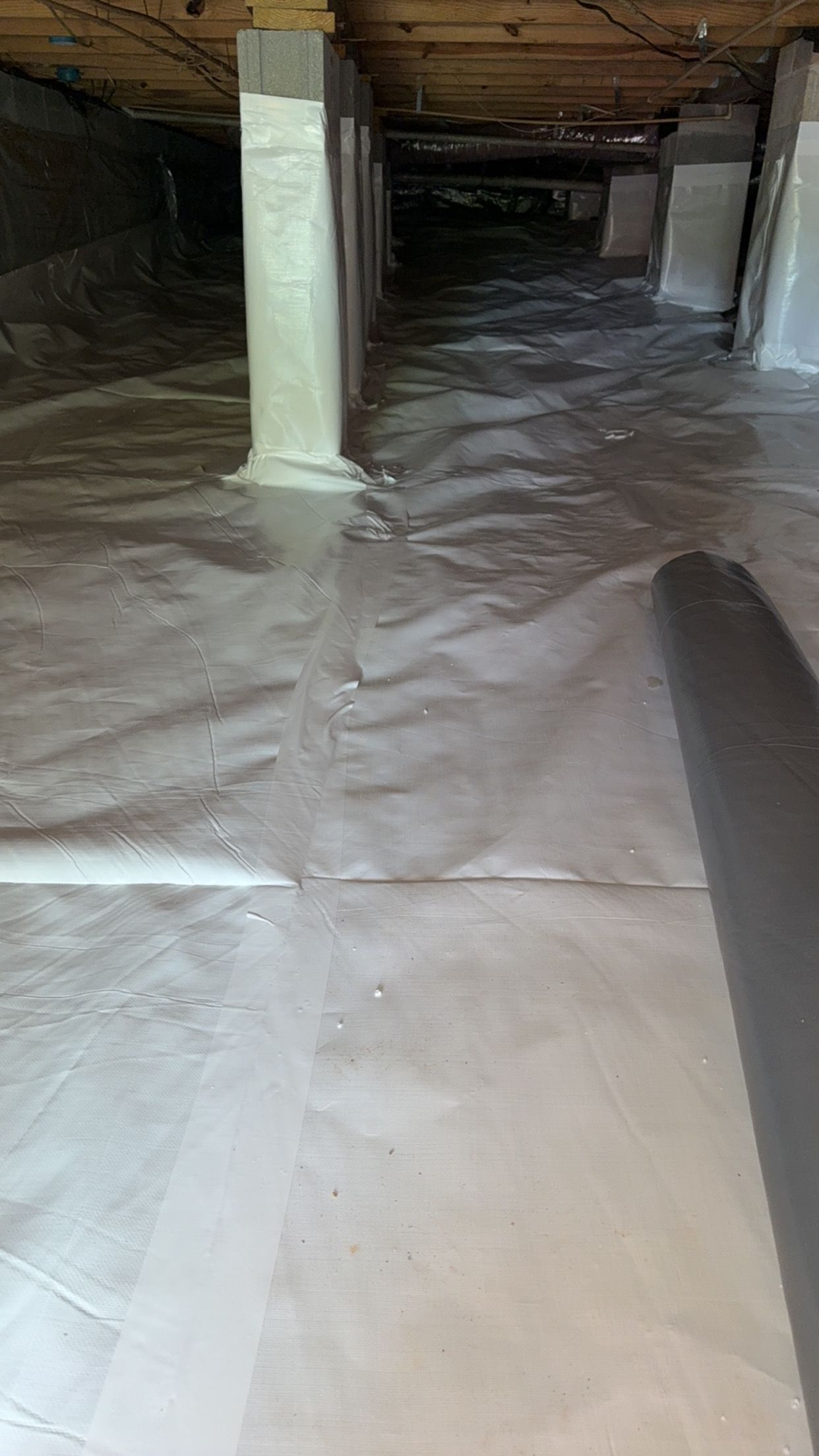 Floodwater rushing through a crawl space under a house with wooden support posts.