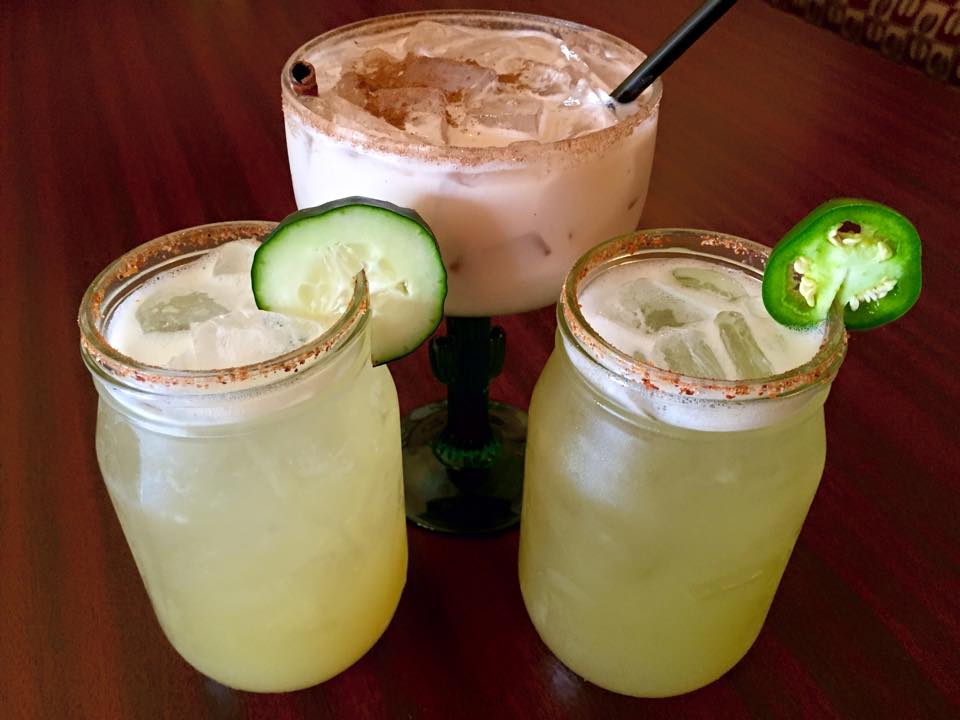 Three different types of drinks are sitting on a wooden table.