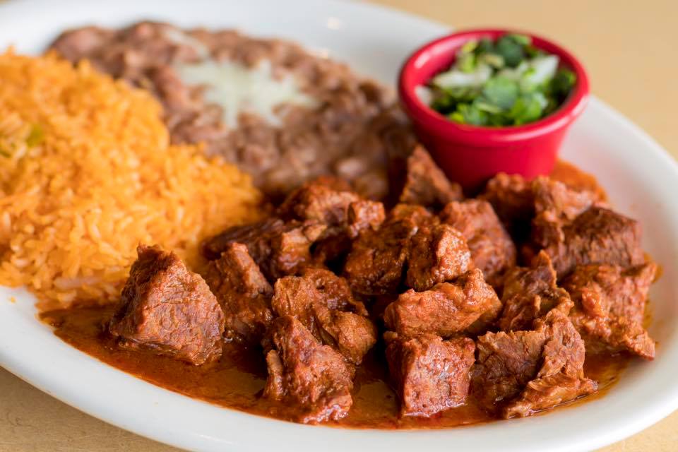 A white plate topped with meat , rice and beans.