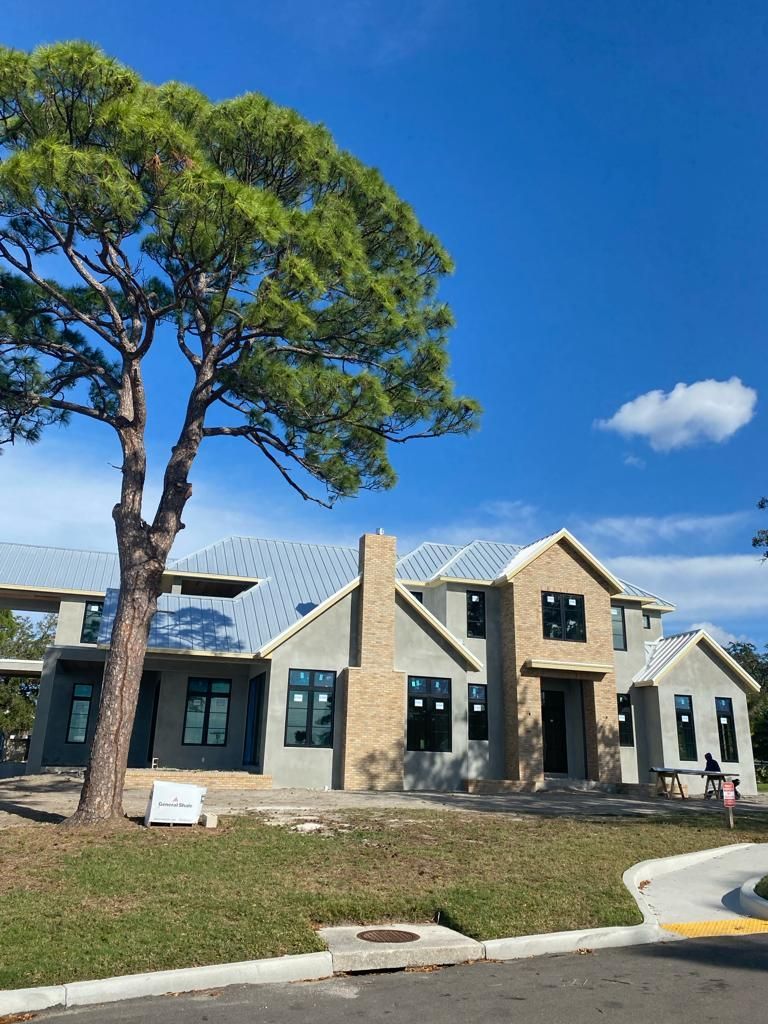 A large house under construction with a tree in front of it.