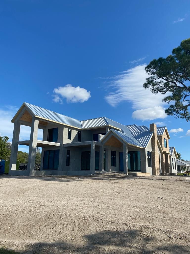 A large house is being built in the middle of a dirt field.