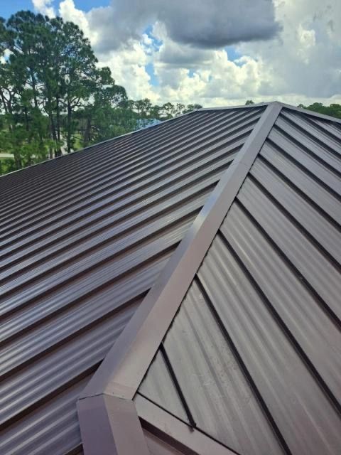 A brown metal roof with trees in the background