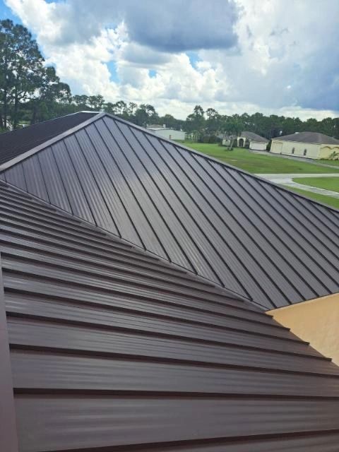 A brown metal roof is being installed on a house