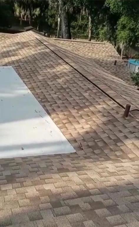A roof with a pool cover on it and trees in the background.