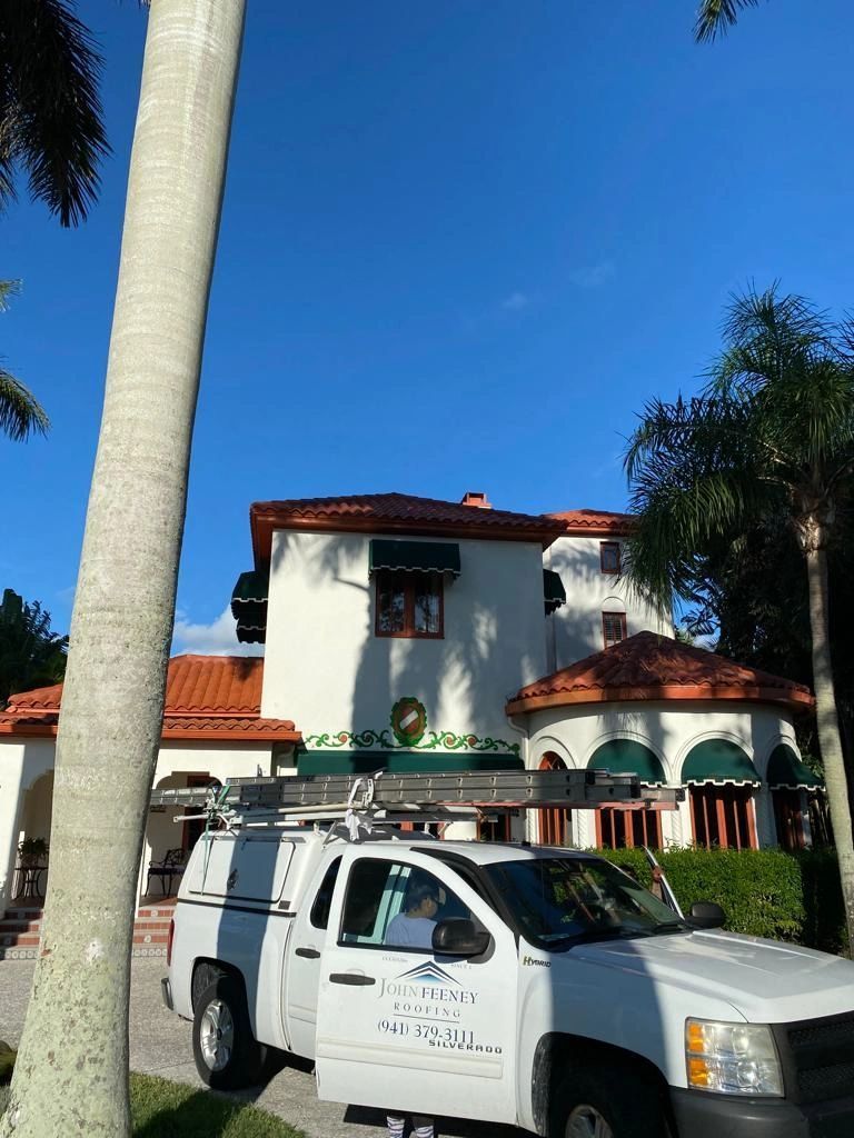 A white truck is parked in front of a large white house.