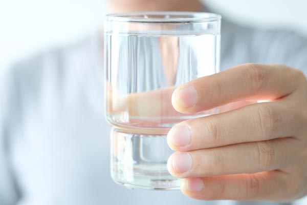 A person is holding a glass of water in their hand.