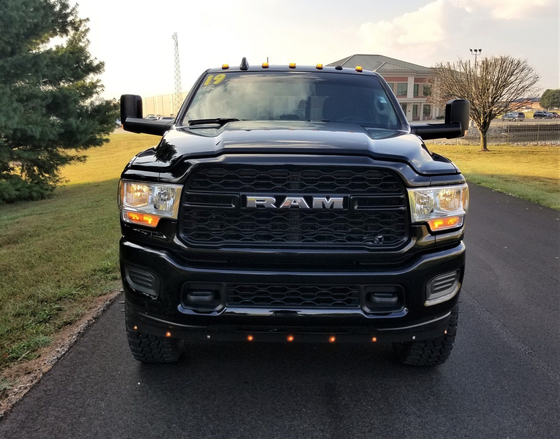 Black RAM pickup truck parked on pavement, facing the camera. The truck has a black grill and orange running lights.