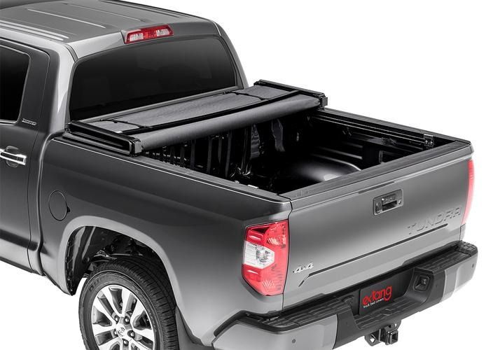 Gray pickup truck with a black, retractable tonneau cover, open over the bed.