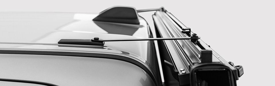 A close-up of the roof of a vehicle, showing a roof rack and antenna.