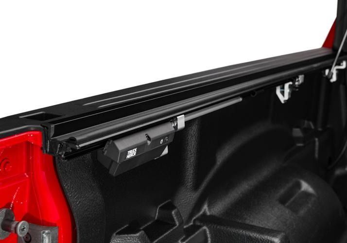 Black truck bed rail with a mounted control box. The bed is red and black with a white background.