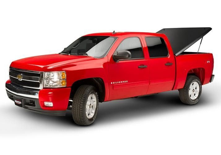 Red Chevrolet Silverado pickup truck with black bed cover in a studio setting.