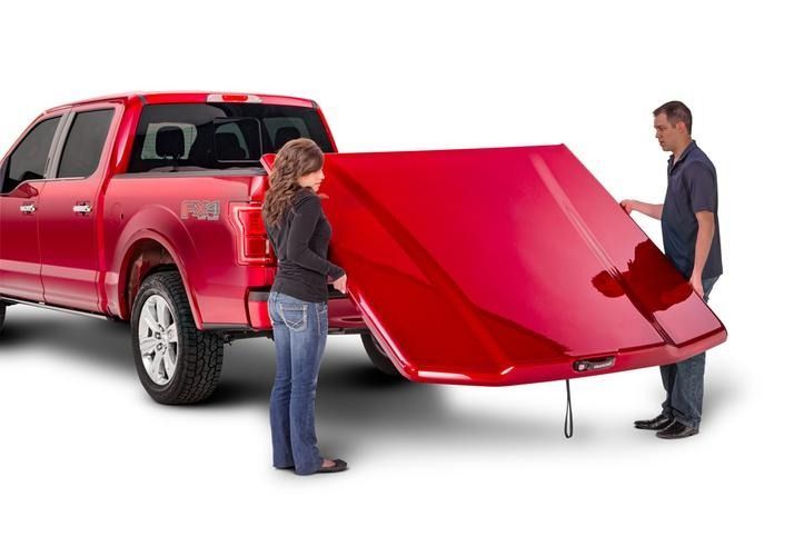 A red pickup truck with a red truck bed cover being installed by a woman and a man.
