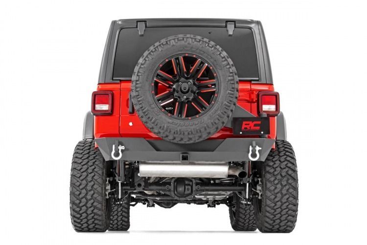 Red Jeep Wrangler from the rear, showing a custom bumper, oversized spare tire, and off-road tires.