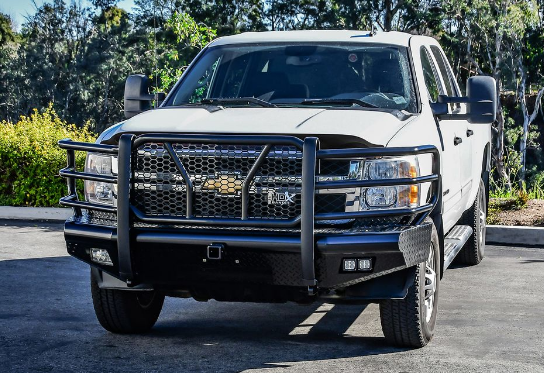 White Chevrolet pickup truck with a black bull bar and off-road accessories parked outdoors on a sunny day.