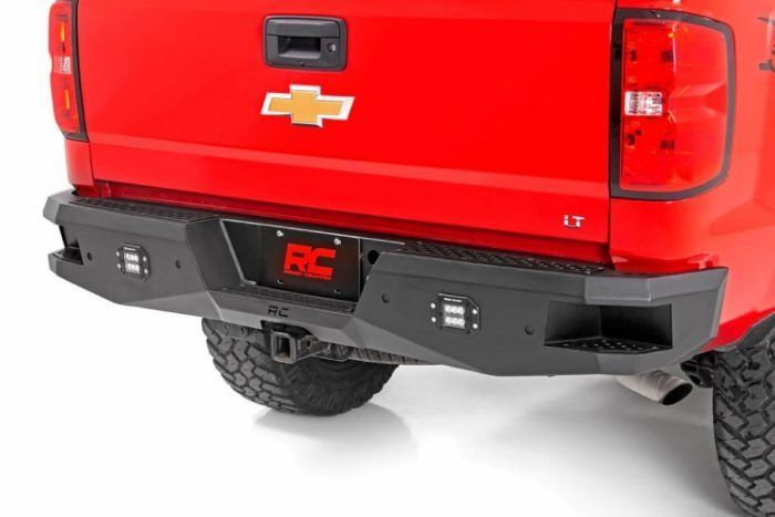 Rear view of a red Chevrolet truck with a black aftermarket bumper. The bumper features integrated lights and a trailer hitch.