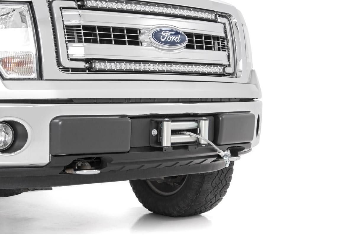 Close-up of a silver Ford truck with a winch mounted on the front bumper.