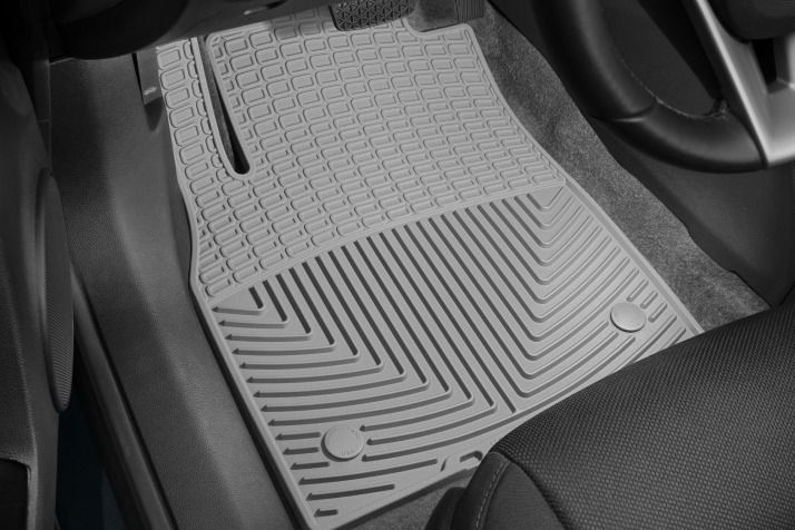 Gray floor mat in a car, covering the driver's side footwell. Features textured surface and molded edges.