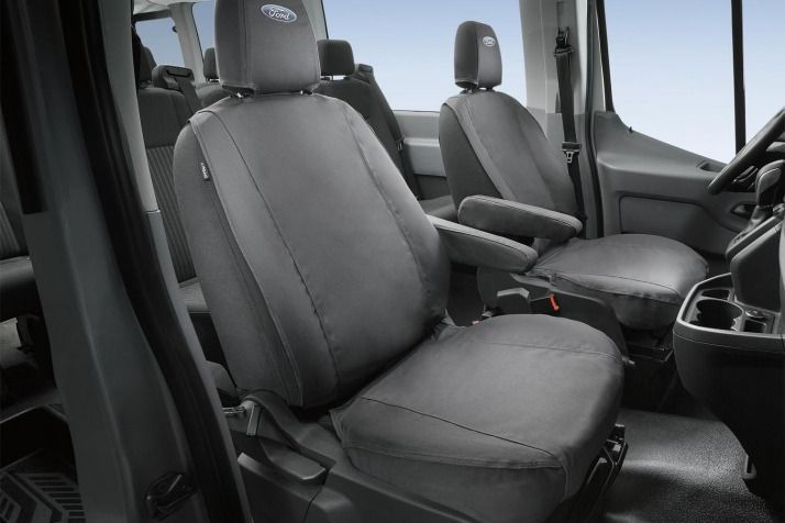 Gray seat covers installed in the front seats of a van, with armrests visible. The driver's side shows a partial steering wheel and cup holders.