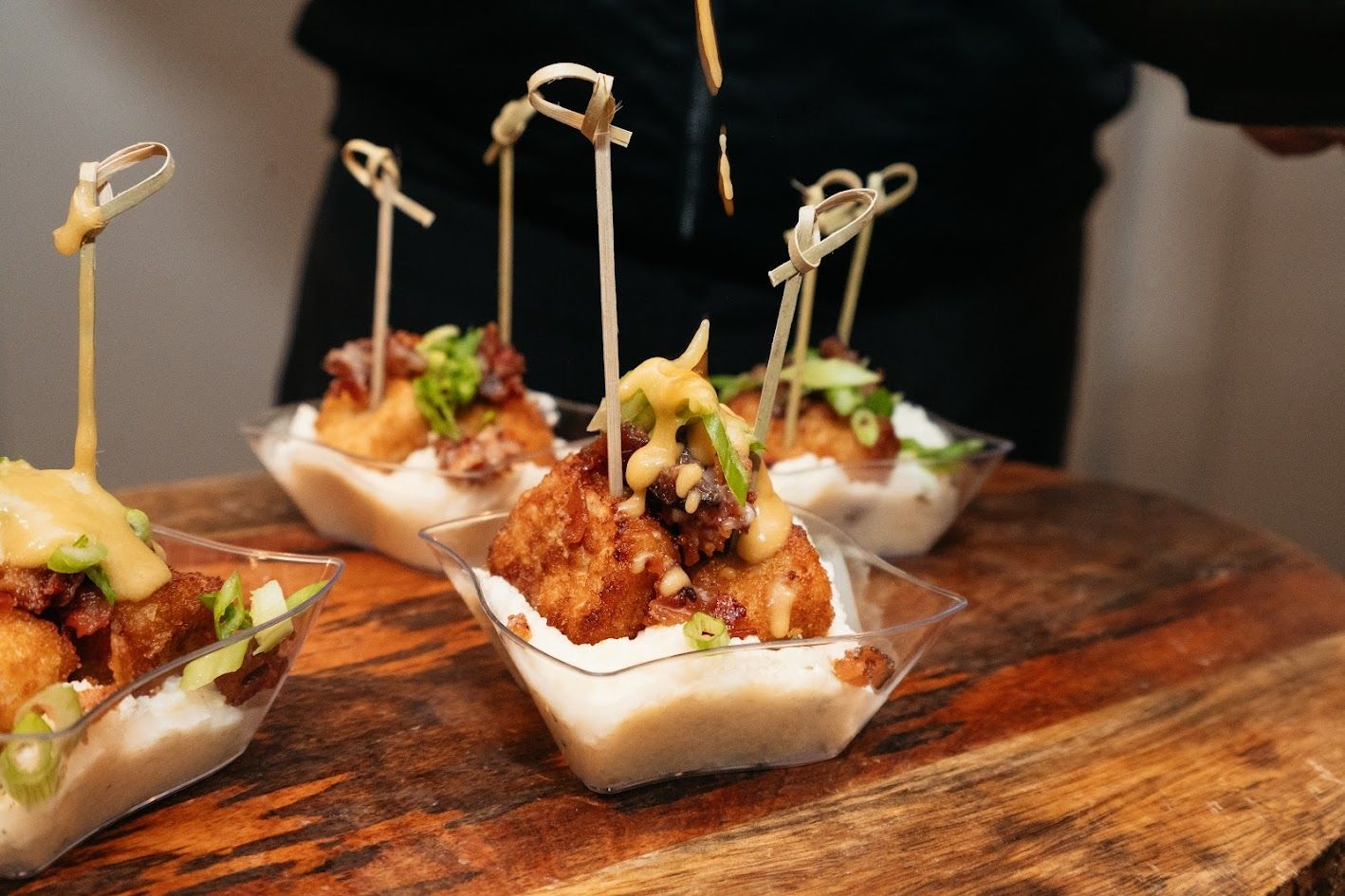 Small appetizer cups with skewers on a wooden board at a catered event