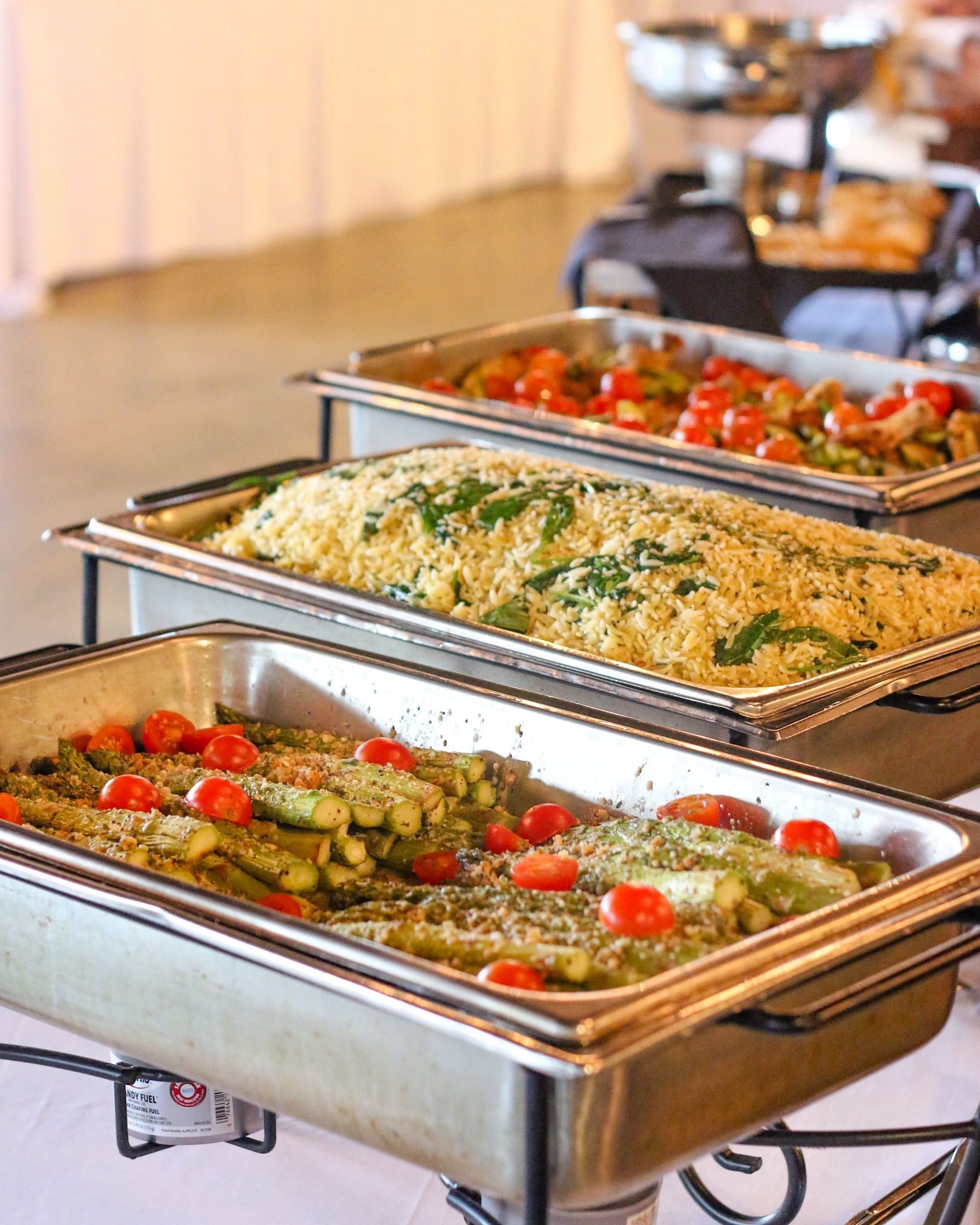 A buffet table with three trays of food on it.