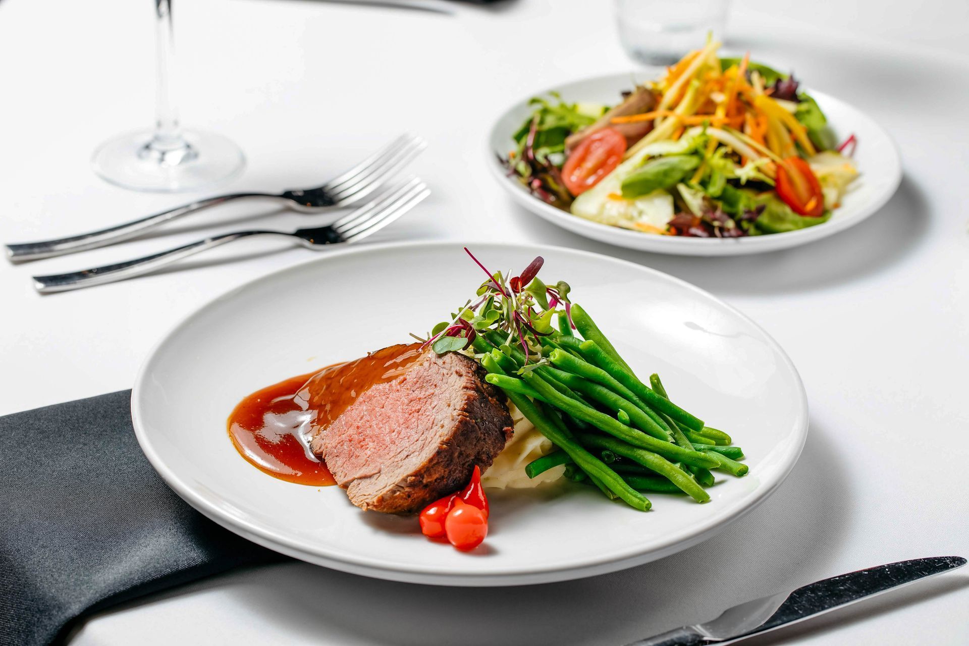 A white plate topped with steak, green beans, mashed potatoes and tomatoes.