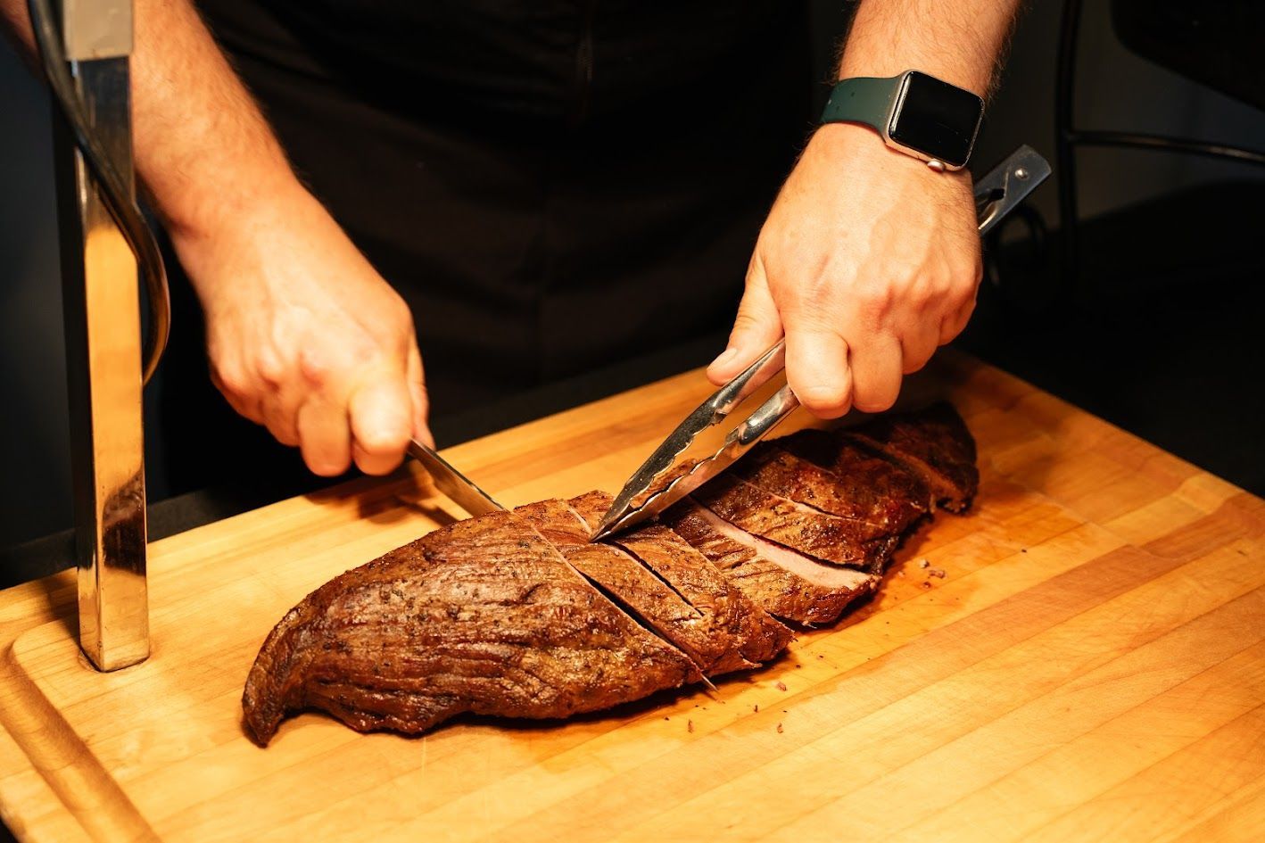 A man is cutting a large piece of meat on a cutting board.