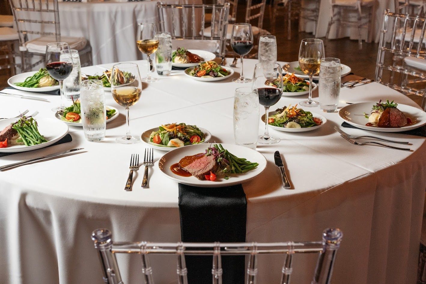 A table with plates of food and wine glasses on it.