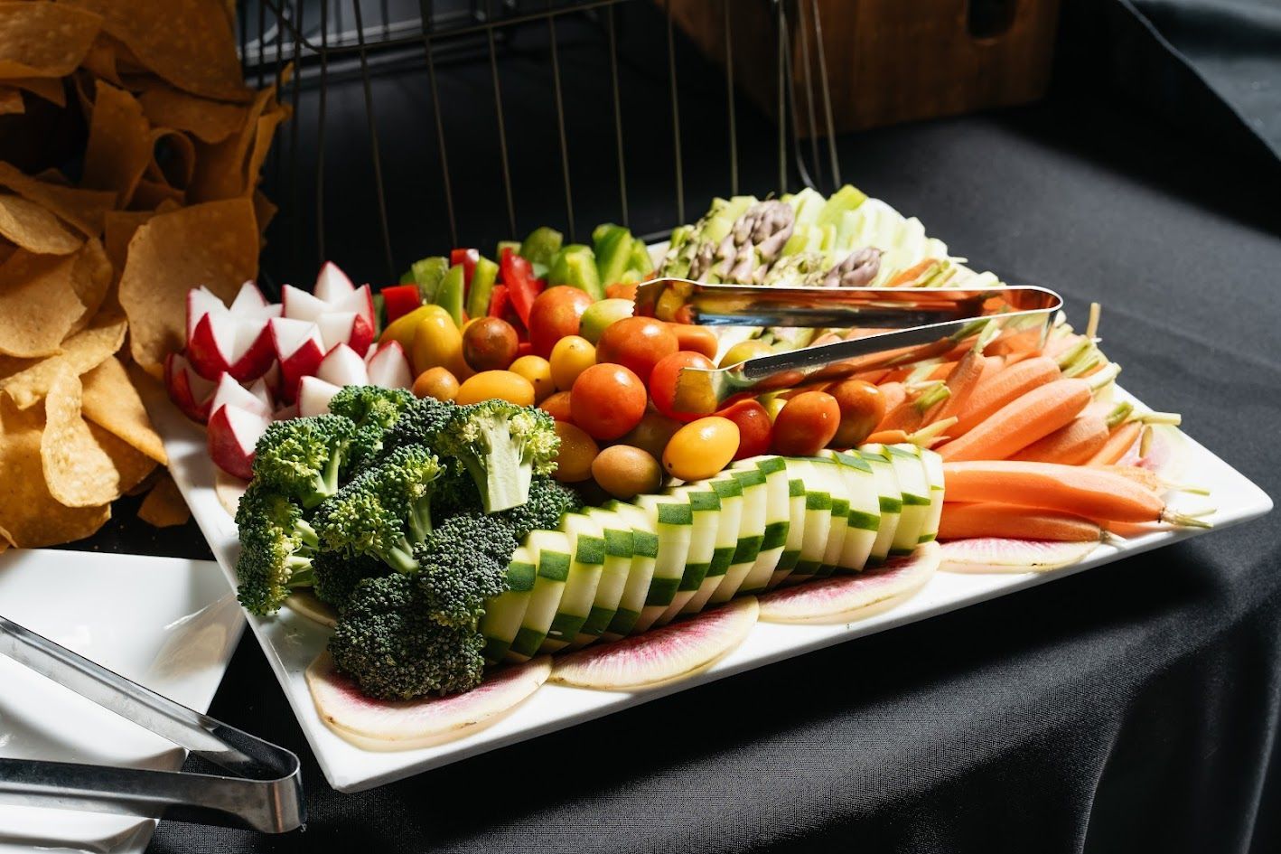 A white plate topped with vegetables and tongs on a table.
