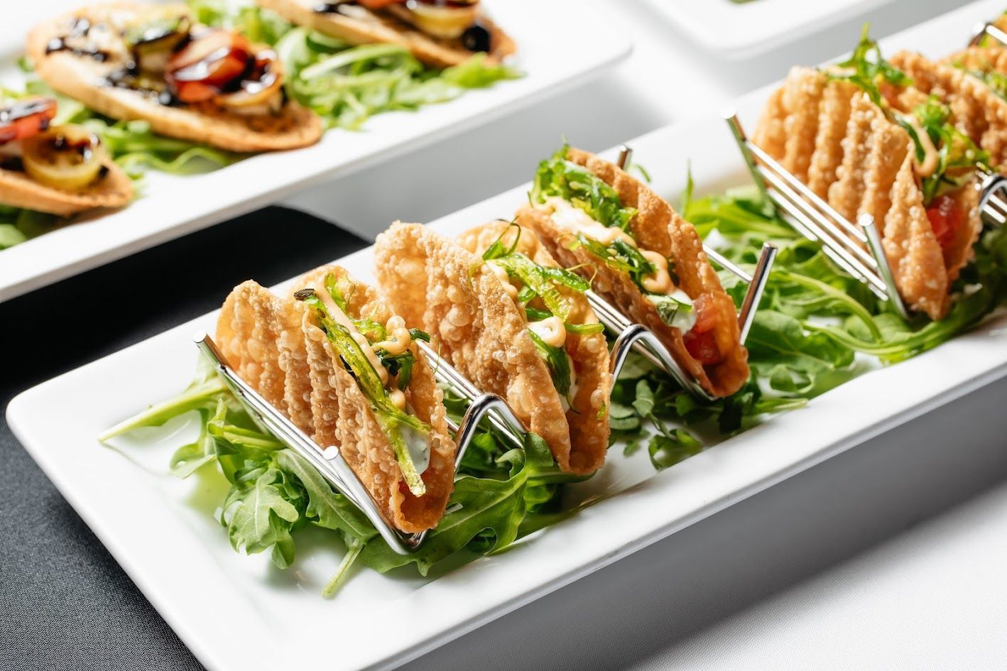 A white plate topped with tacos and lettuce on a table.