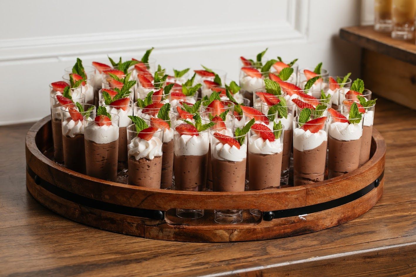 A wooden tray filled with chocolate mousse and strawberries.