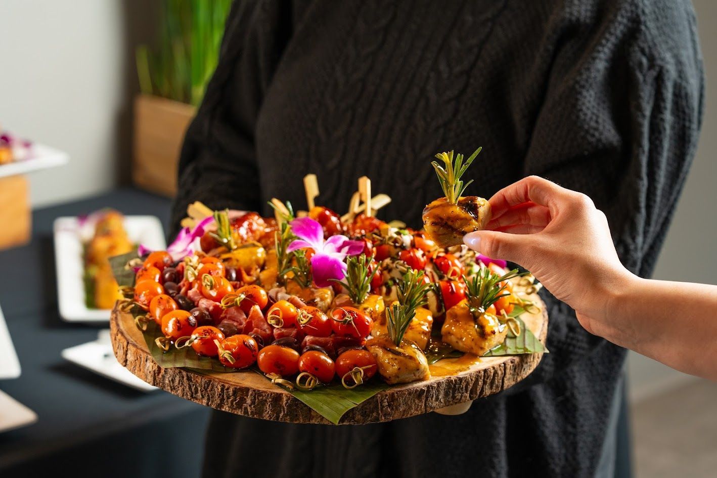 A person is holding a tray of food on a wooden cutting board.