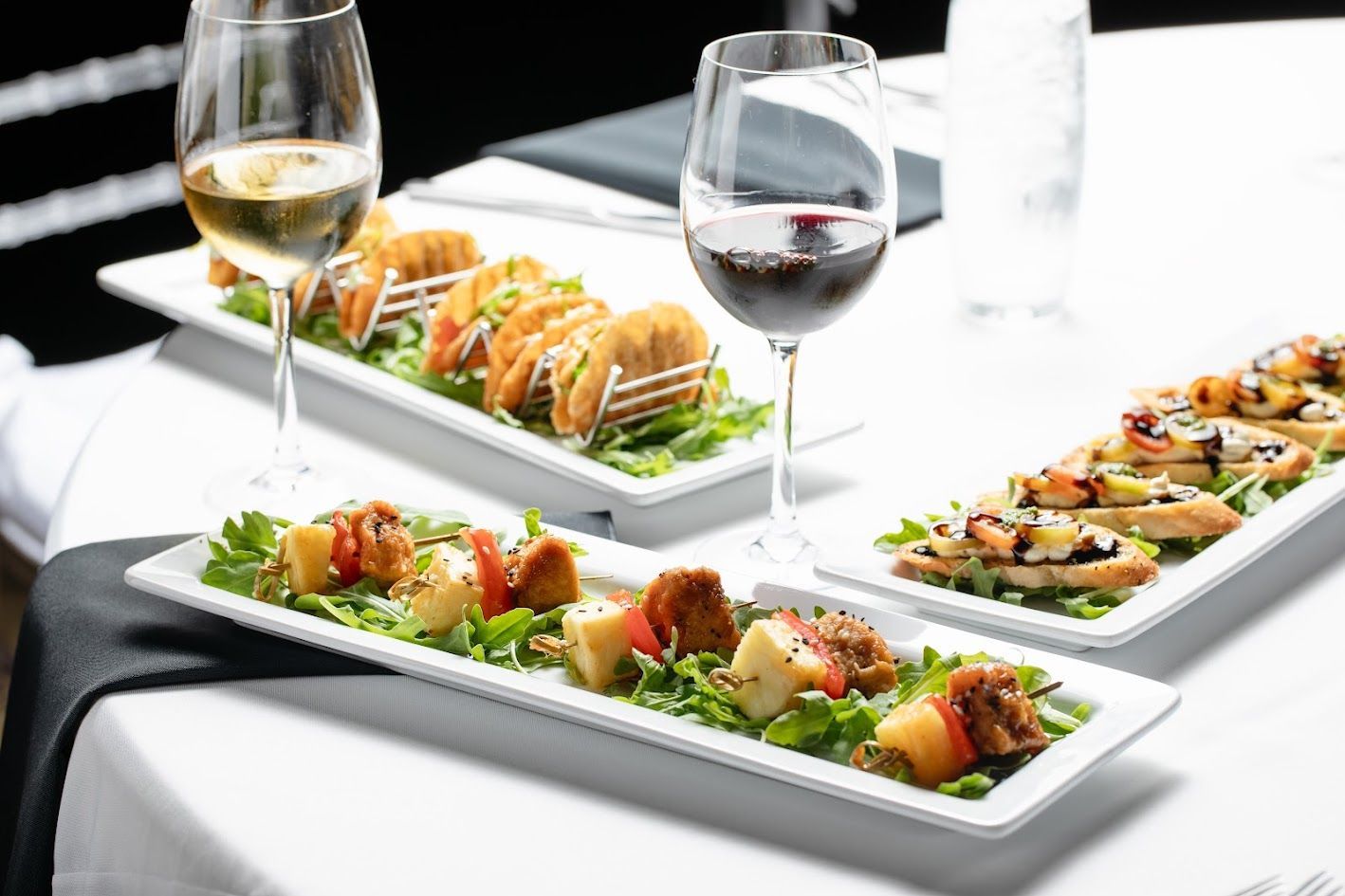 Elegant plated appetizers with wine glasses on a white table