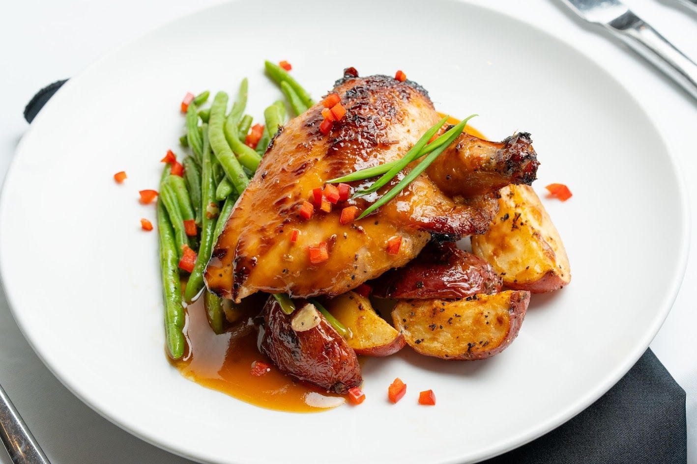 Roasted chicken with green beans and sauce on a white plate