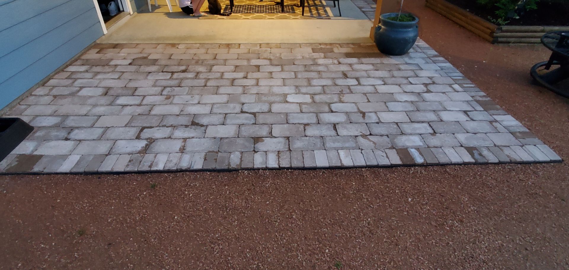 Wooden-shingled patio with a large blue pot, surrounded by small red gravel.