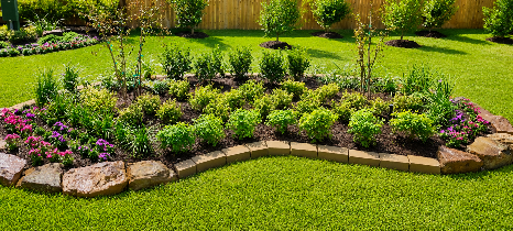 Curved flower bed with pink and yellow blooms in a neatly landscaped green garden