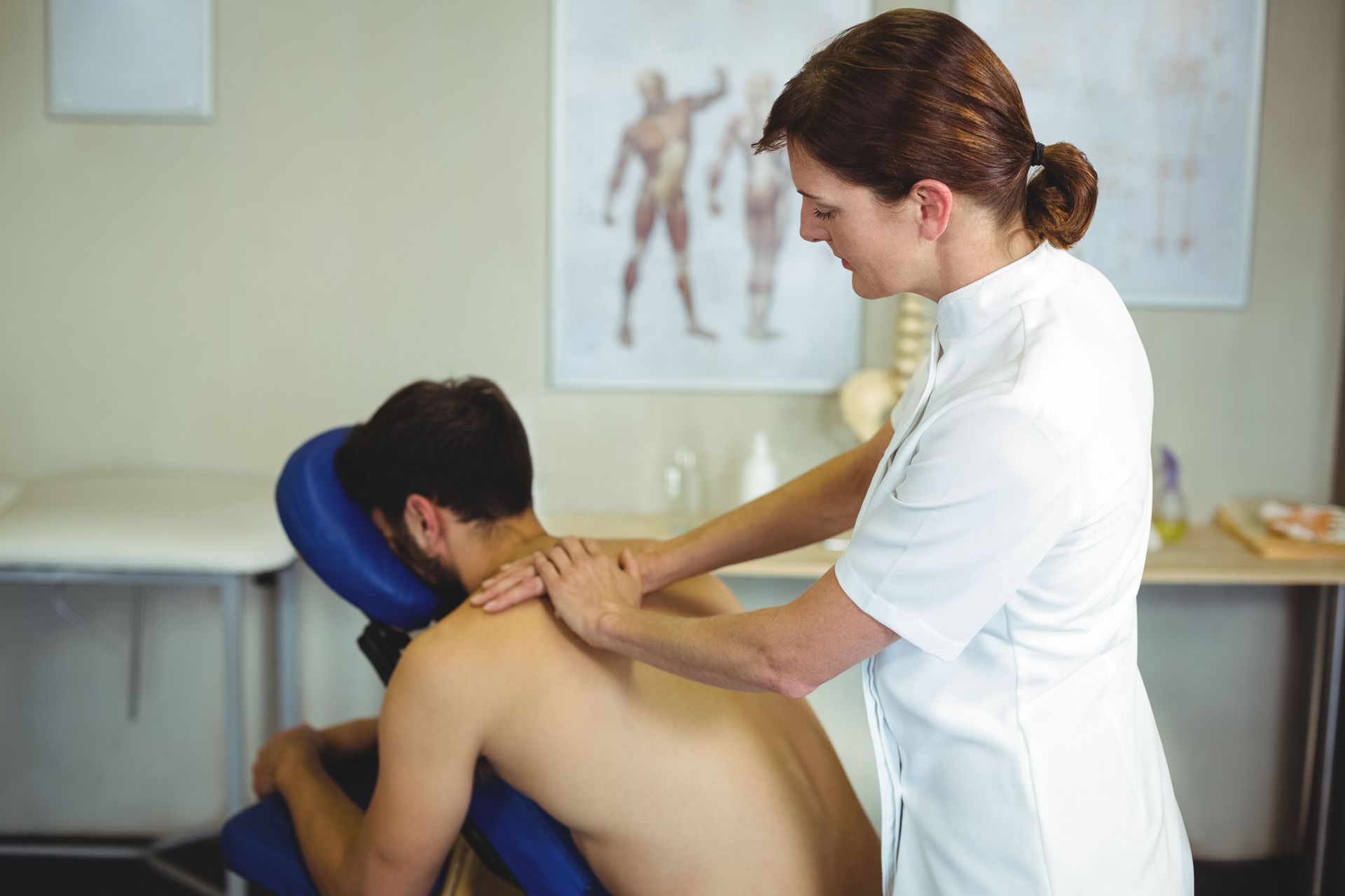 Therapist performing a neck and shoulder massage on a patient in a clinic room