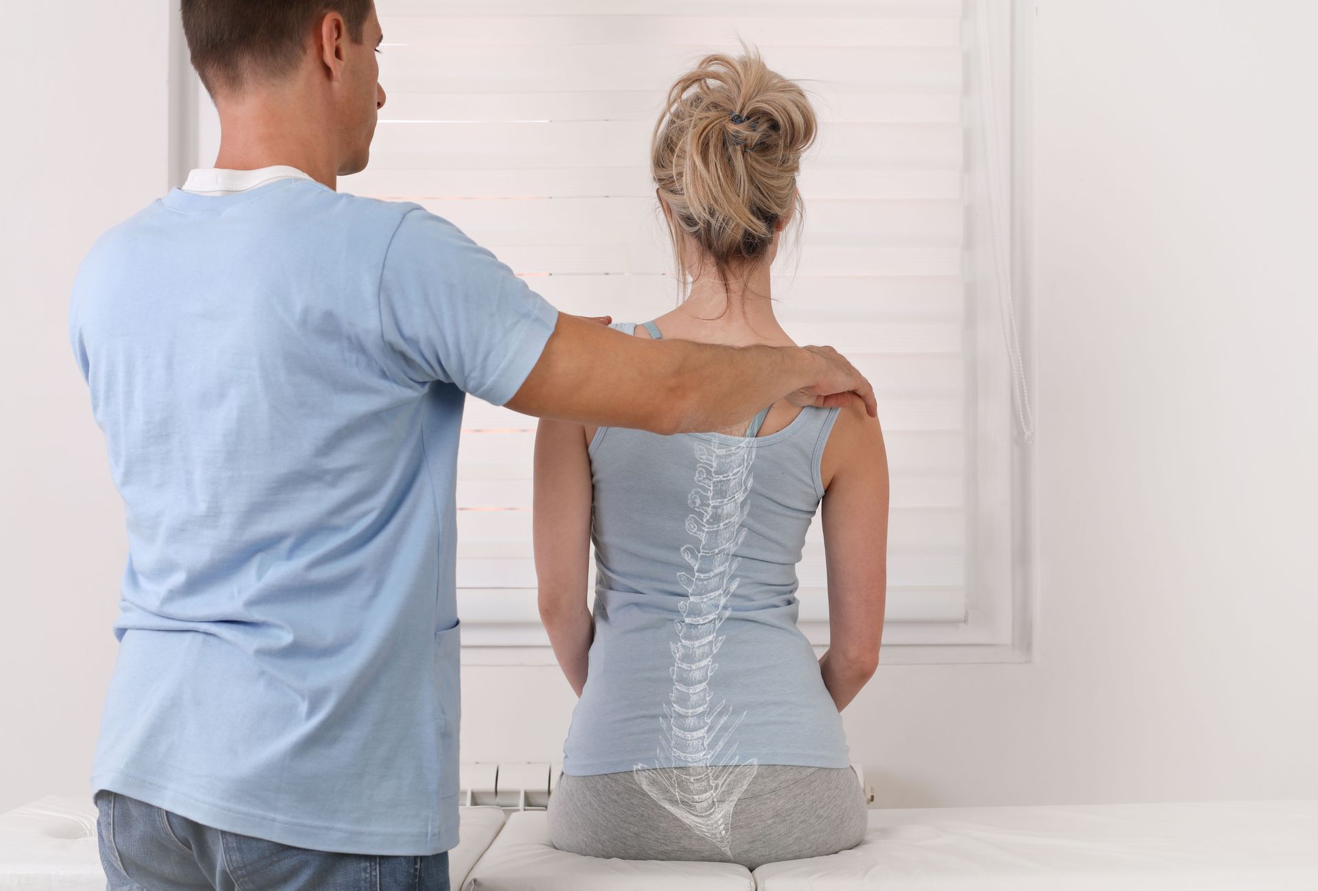 Man in blue shirt comforting a seated woman in a silver top from behind in a bright room