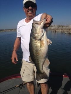 Man holding a large fish on a boat in calm water under a clear blue sky