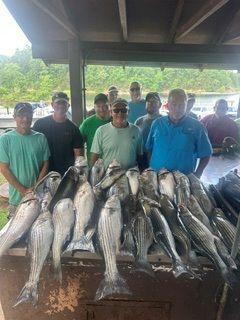 Group standing behind a table covered with many large fish under a covered outdoor area