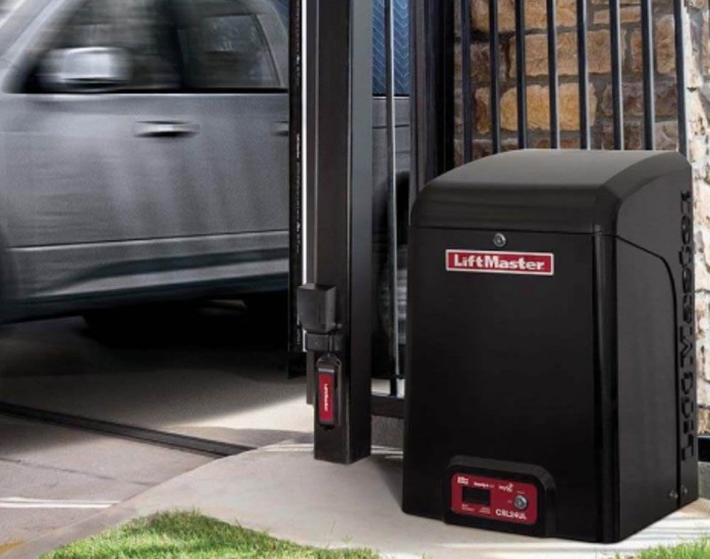 LiftMaster automatic gate opener beside a sliding driveway gate as a car passes through